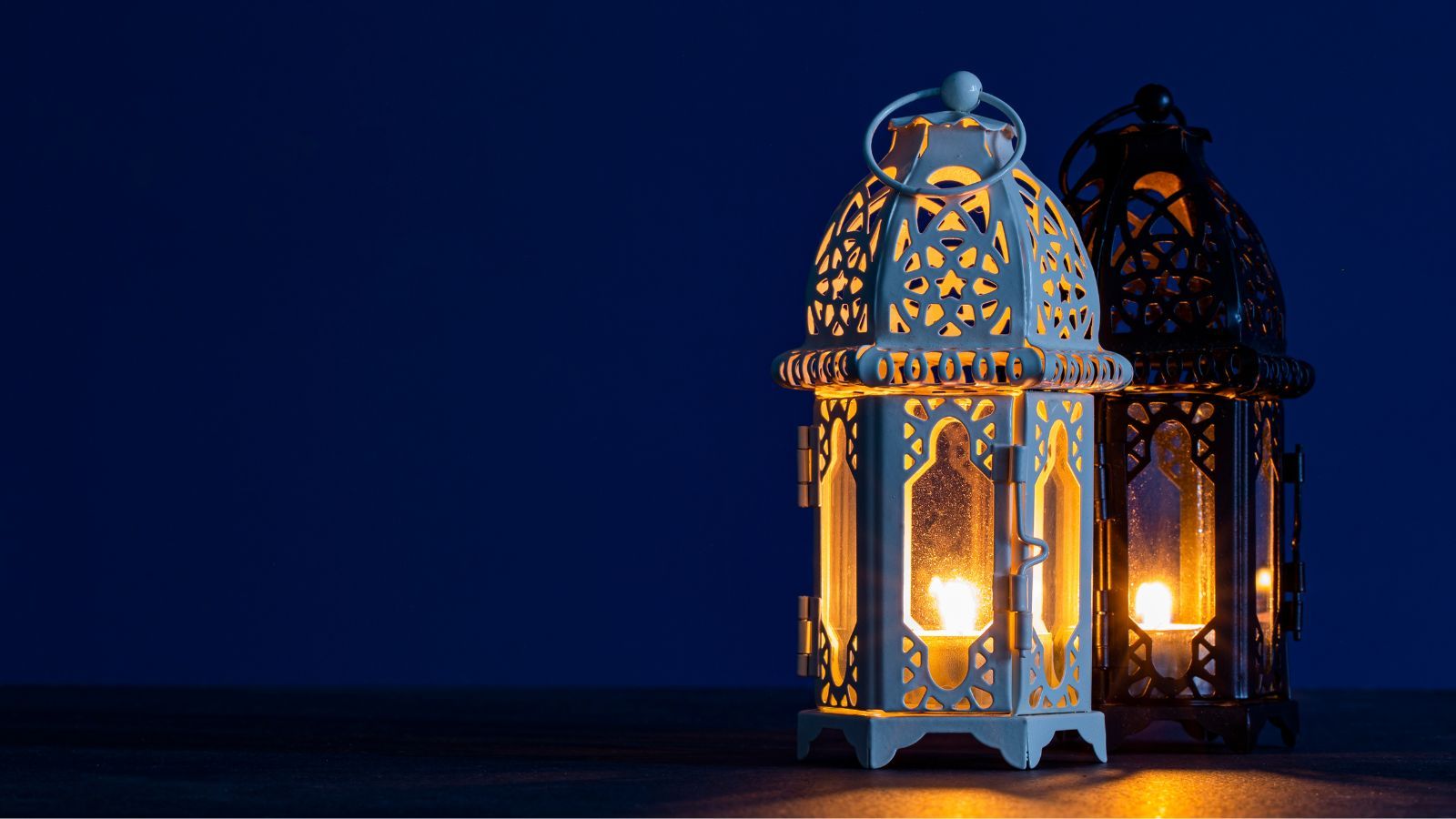An ornately carved lantern glows with a lit candle, lighting up the darkness