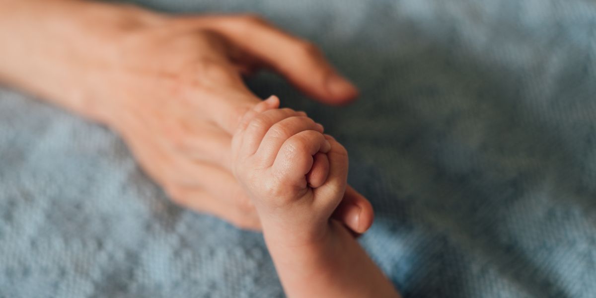 a baby fist grabbing an adult's finger