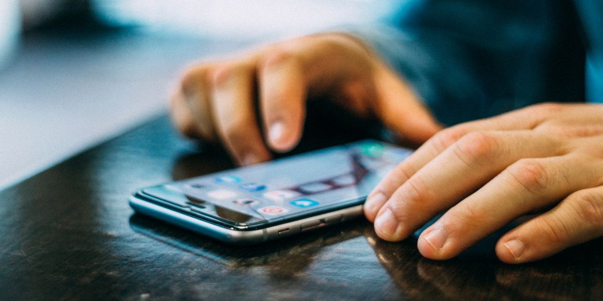 Hands dialling a number on a mobile phone that is resting on a table