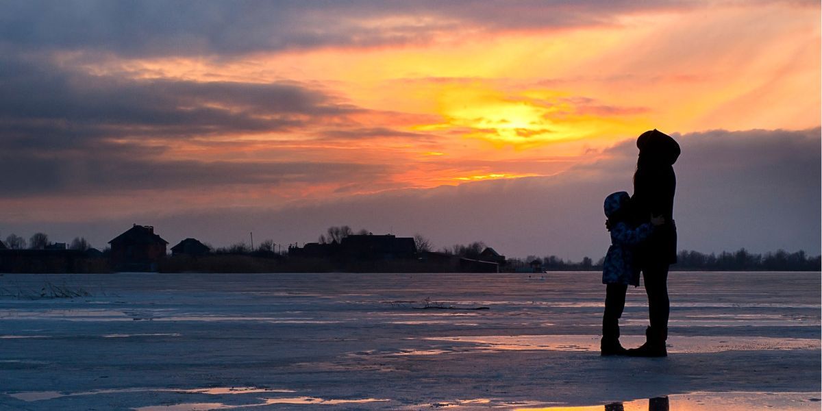 photo of a sun set landscape with a mother and child hugging in sihouette